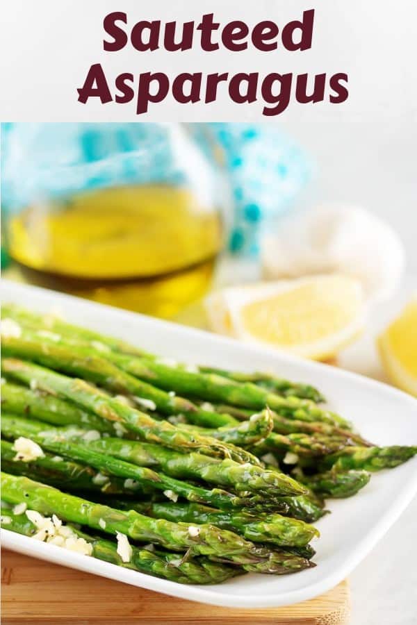 The sauteed asparagus, topped with garlic, served on a rectangular plate.