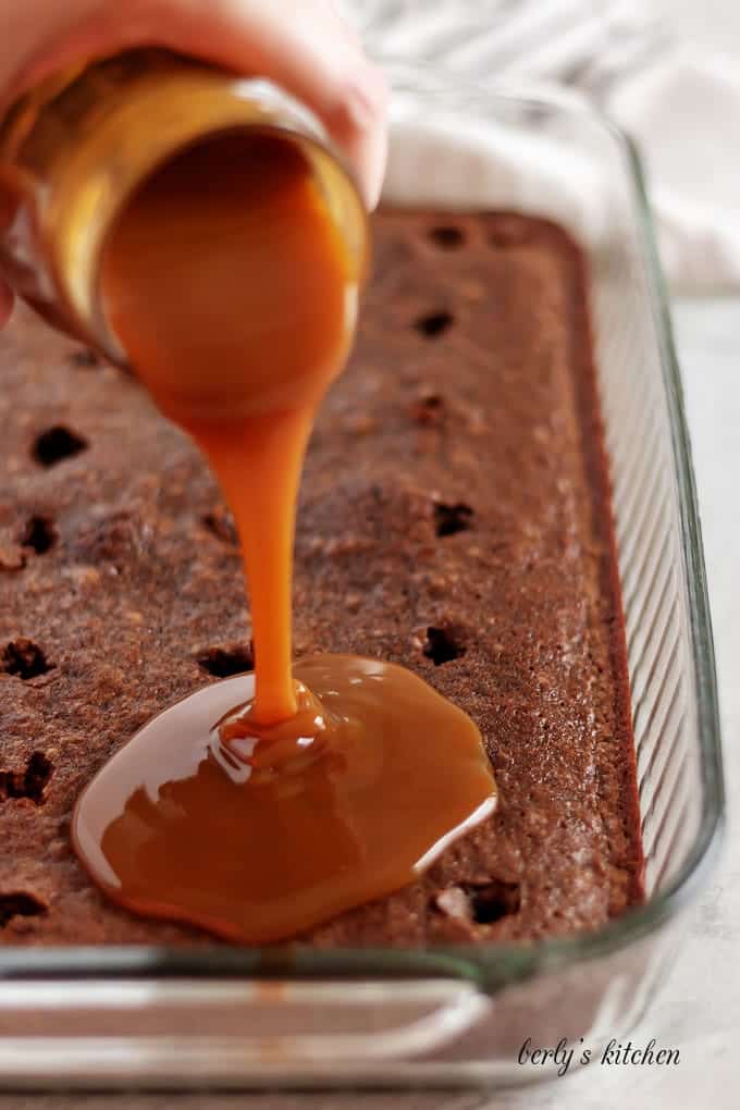 The caramel sauce pouring over the baked and poked brownies.