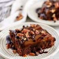 Two big squares of turtle brownies served on white plates.