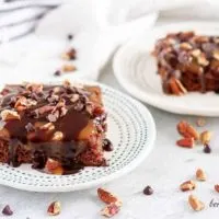 Two turtle brownies covered in chocolate ganache and sweet caramel.