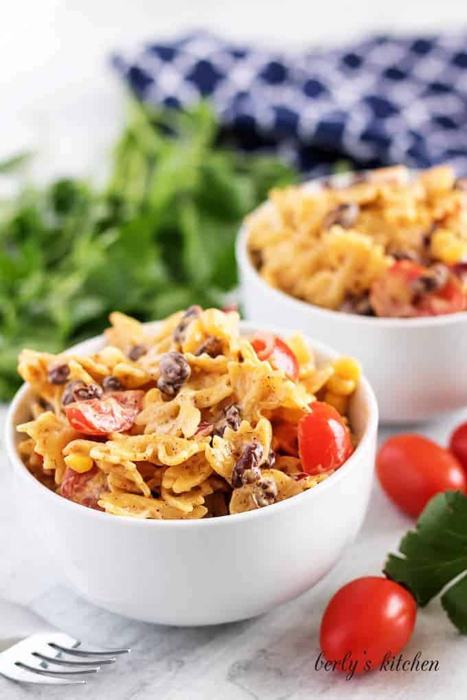 The dish being served in white bowls garnished with fresh tomatoes.