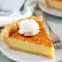 A large piece of buttermilk pie topped with whipped cream.