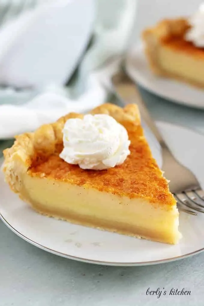 A large piece of buttermilk pie topped with whipped cream.