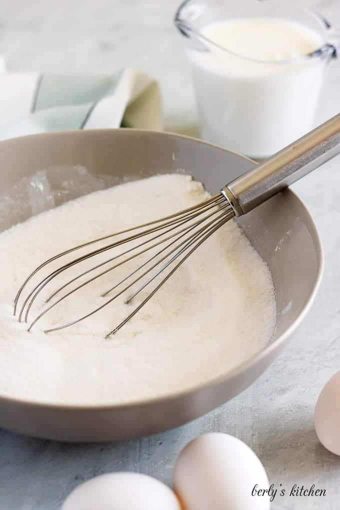 The flour and sugar being combined in a large metal bowl.