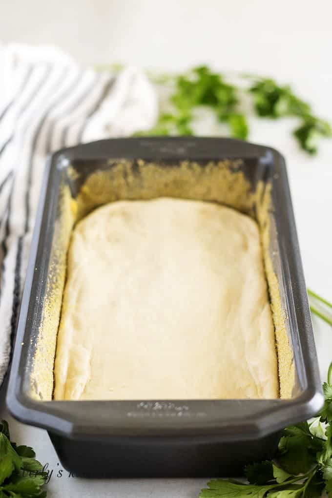 The english muffin bread dough in a baking dish preparing to rise.