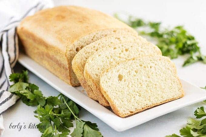 The loaf of english muffin bread sliced and sitting on a plate.