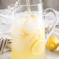 The serving pitcher being filled with the fresh made lemonade.