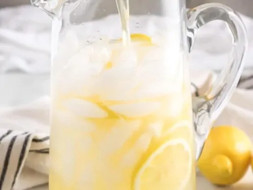 The serving pitcher being filled with the fresh made lemonade.