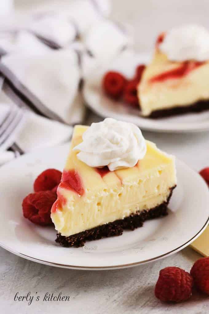 Slices of instant pot white chocolate raspberry cheesecake topped with whipped cream.