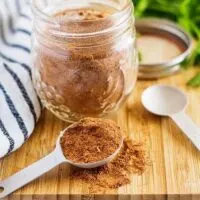 A mason jar filled with taco seasoning sitting on a cutting board.