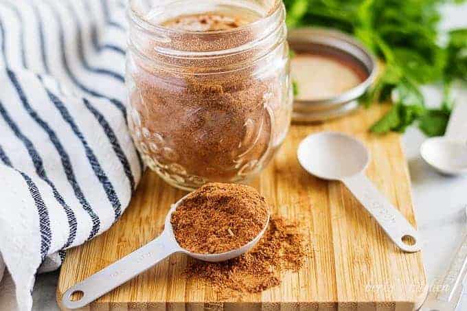 A mason jar filled with homemade taco seasoning on a cutting board.