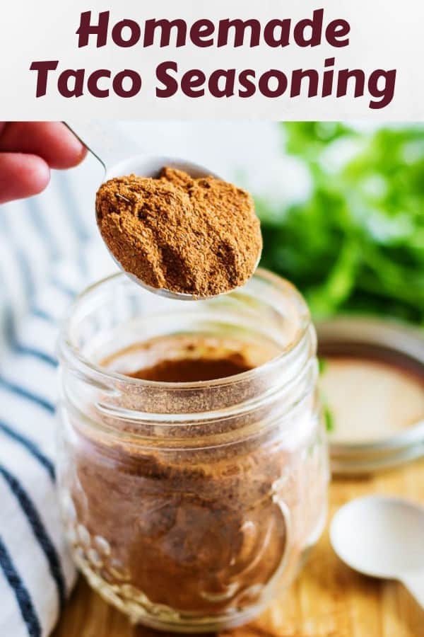 Homemade taco seasoning being scooped from a small mason jar.