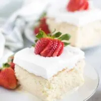 A slice of tres leches cake sitting on a white saucer.