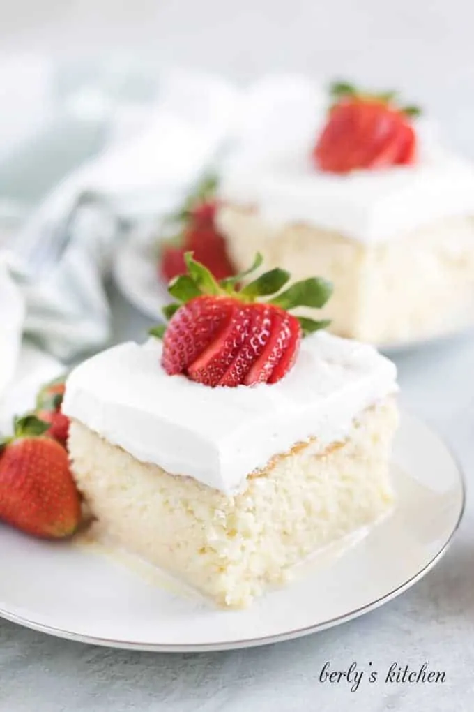 A slice of tres leches cake sitting on a white saucer.