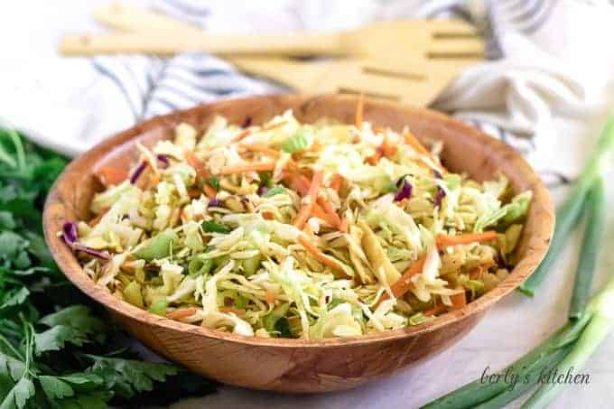 The asian salad served in a wooden bowl, tossed with dressing.