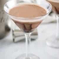 Two chocolate martinis in martini glasses on a marble table top.