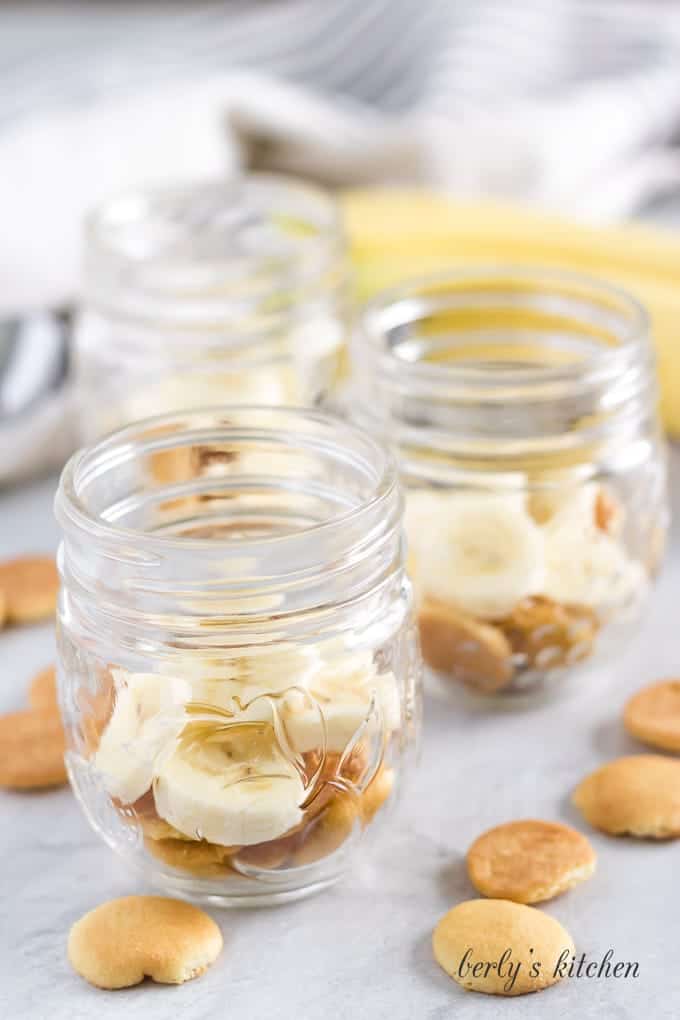 Vanilla wafers and sliced bananas in the bottom of a mason jar.