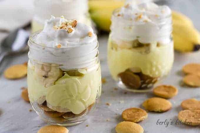 Two mini mason jars filled with banana pudding topped with whipped cream.