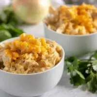 Two bowls of ranch style chicken and rice topped with shredded cheddar.