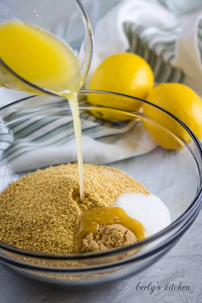 Melted butter being poured over the sugar and graham cracker crumbs.