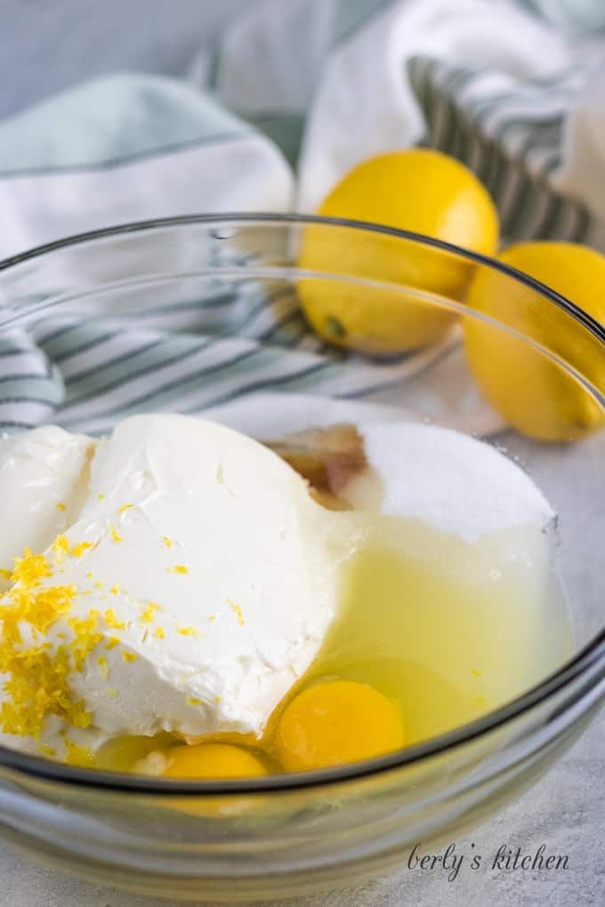 Sugar, cream cheese, and other cheesecake filling ingredients in a mixing bowl.