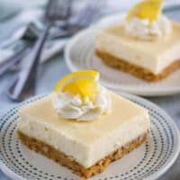 The lemon cheesecake bars garnished with whipped cream, and lemon wedges.
