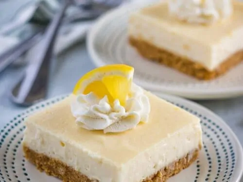The lemon cheesecake bars garnished with whipped cream, and lemon wedges.
