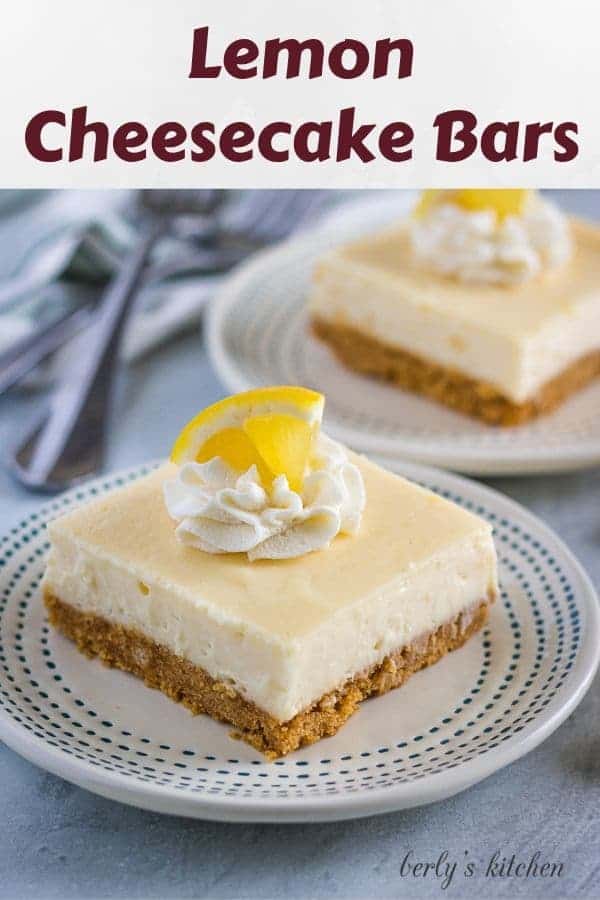Two lemon cheesecake bars garnished with whipped cream and lemon wedges.