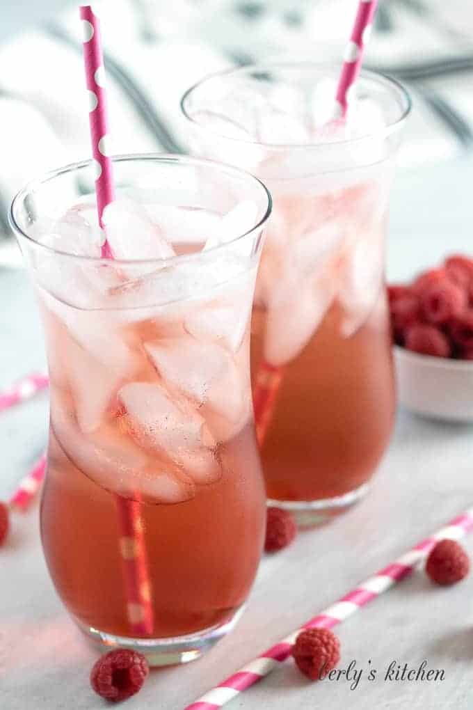 Two glasses of finished italian soda served with ice and a straw,