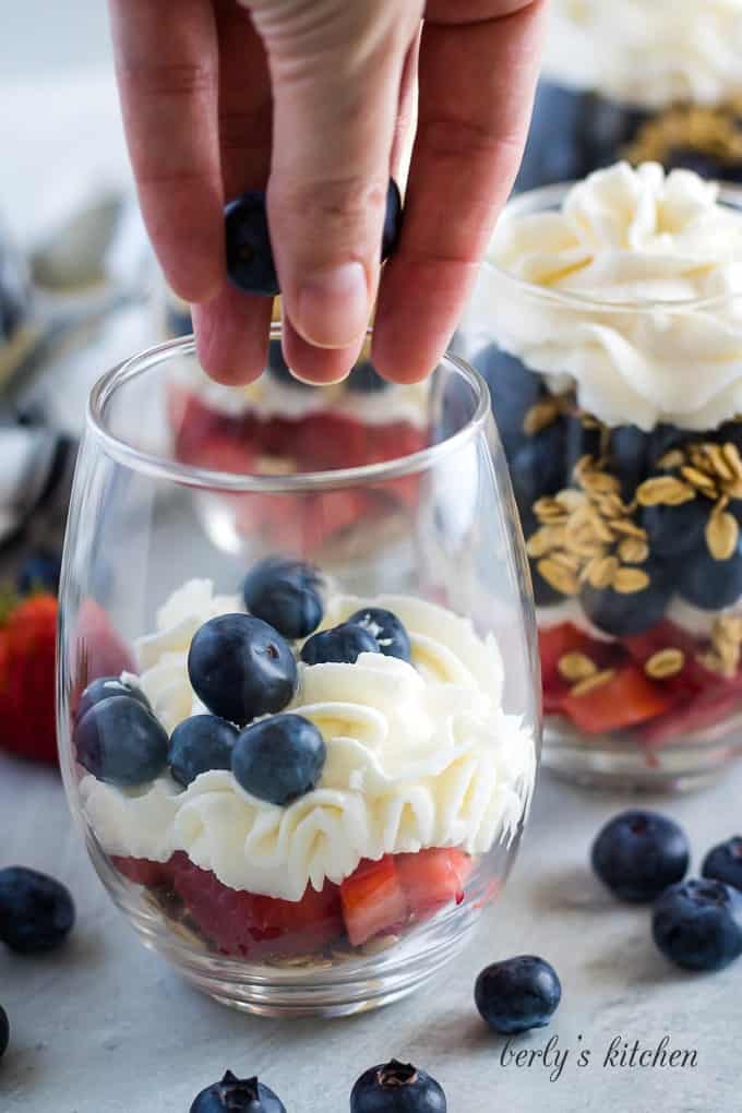 The fresh blueberries being added to the glass for layer four.