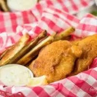 A filet of beer battered cod served with fries and tartar sauce.