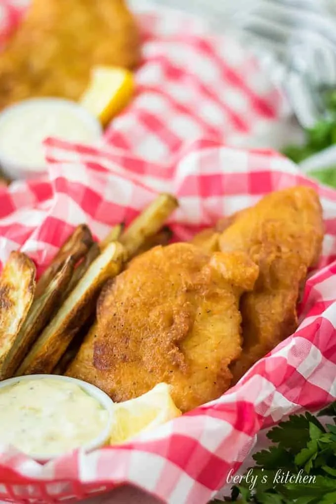 Fried fish, in a basket, served with fries and tartar sauce.