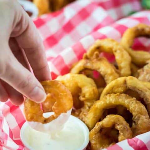 Kimberly dipping an onion ring into the ramekin of ranch dressing.
