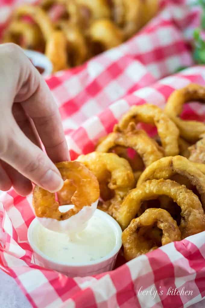Kimberly dipping an onion ring into the ramekin of ranch dressing.