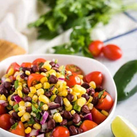 Corn And Black Bean Salsa The final photo showing the dip surrounded by fresh peppers and tomatoes.