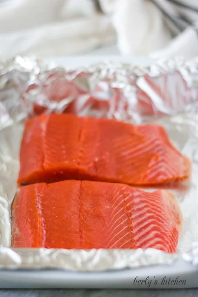 The fish has been placed in a foil lined baking dish.