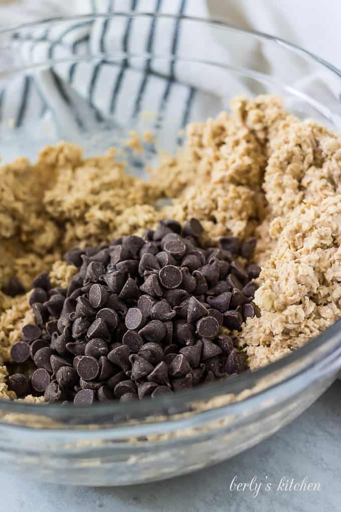 A cup of chocolate chips have been poured into the bowl.