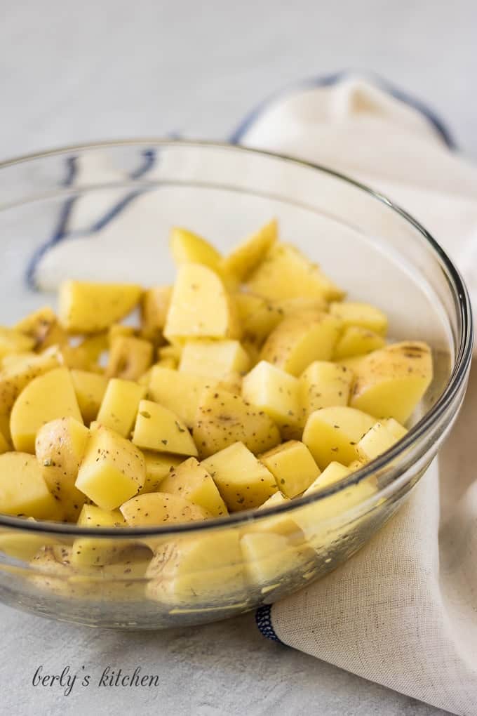 A large glass mixing bowl filled with diced golden potatoes.