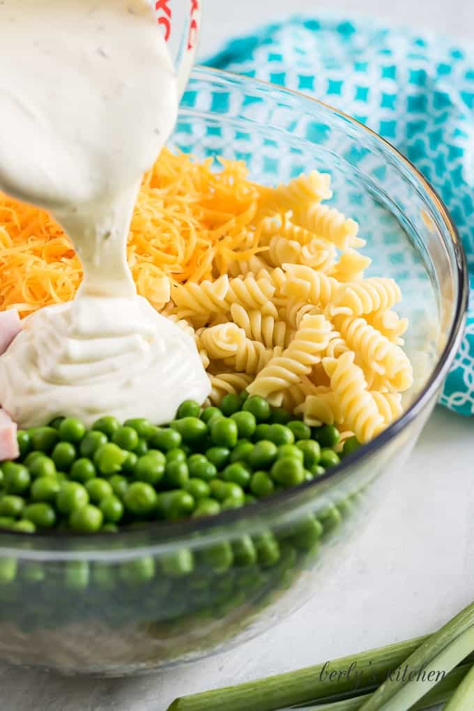 The creamy ranch dressing being poured over all the ingredients.