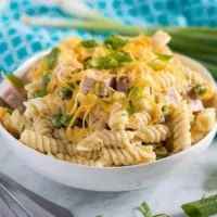 A large, white bowl of the ham and cheese pasta salad.