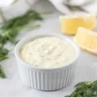 The homemade tartar sauce served in a ramekin surrounded by fresh dill.