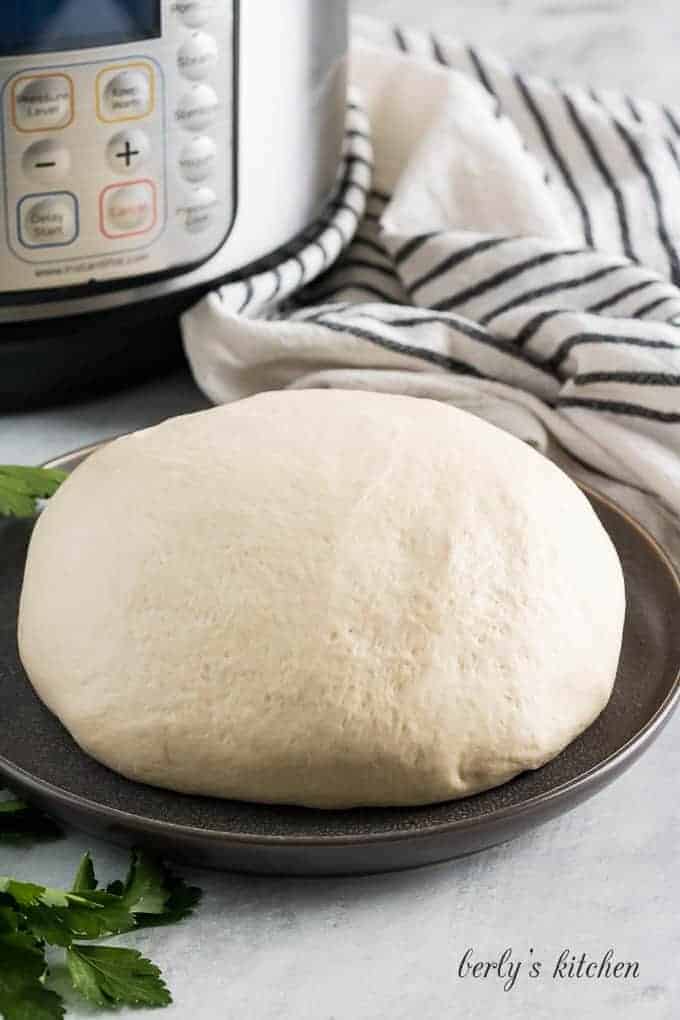 Proofed pizza dough on a gray plate.