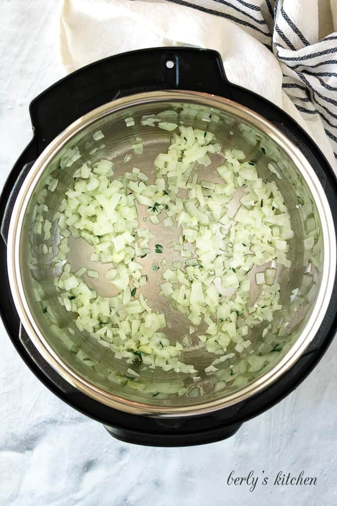 Melted butter with diced onions being sauteed in the pressure cooker.