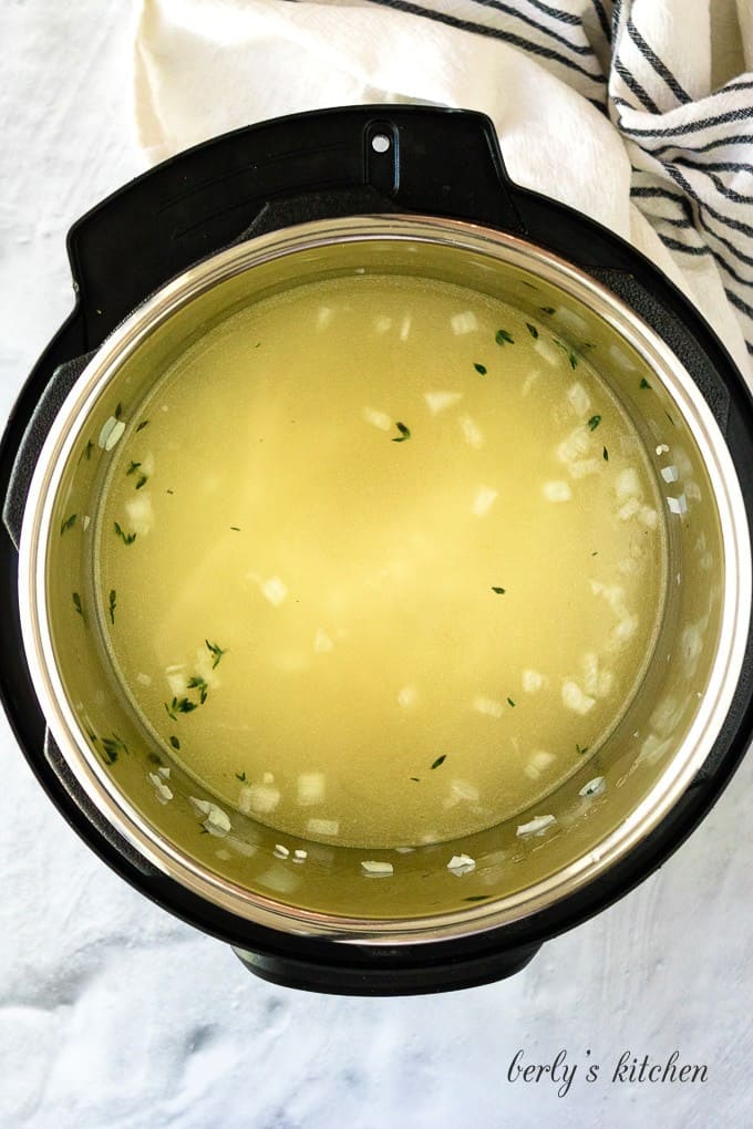 Broth has been added to the cooker to cover the toasted rice.