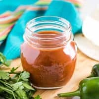 The red enchilada sauce in a mason jar accented with jalapenos.