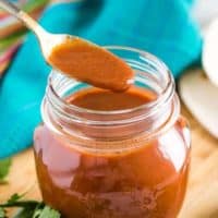 A spoonful of the sauce held over the opened mason jar.