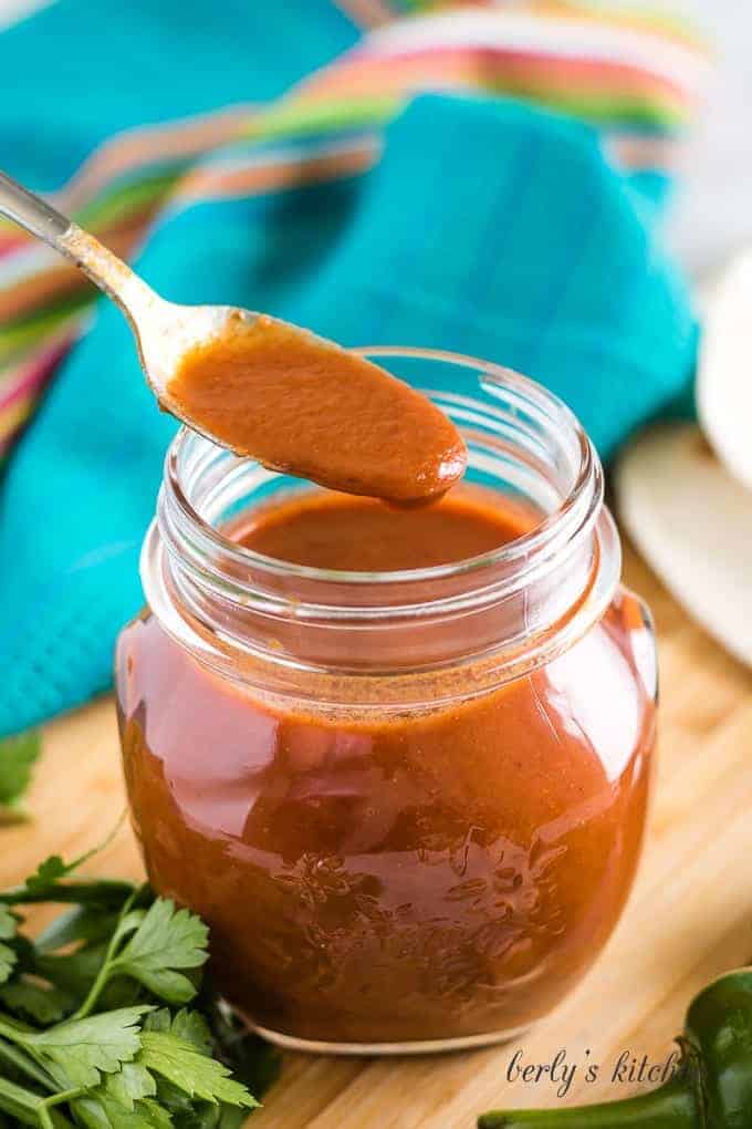 A spoonful of the sauce held over the opened mason jar.