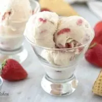Three scoops of strawberry ice cream in a small cocktail glass.
