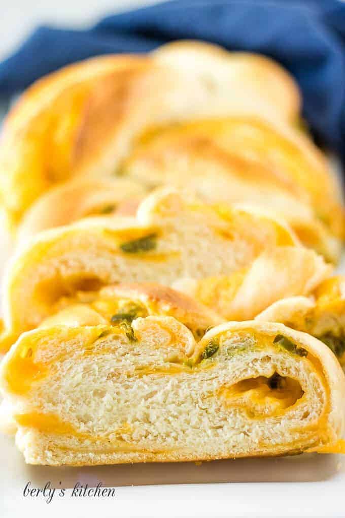 A loaf of jalapeno cheese bread with a blue linen.