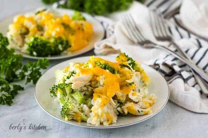 Two plates of the chicken broccoli rice topped with cheddar.